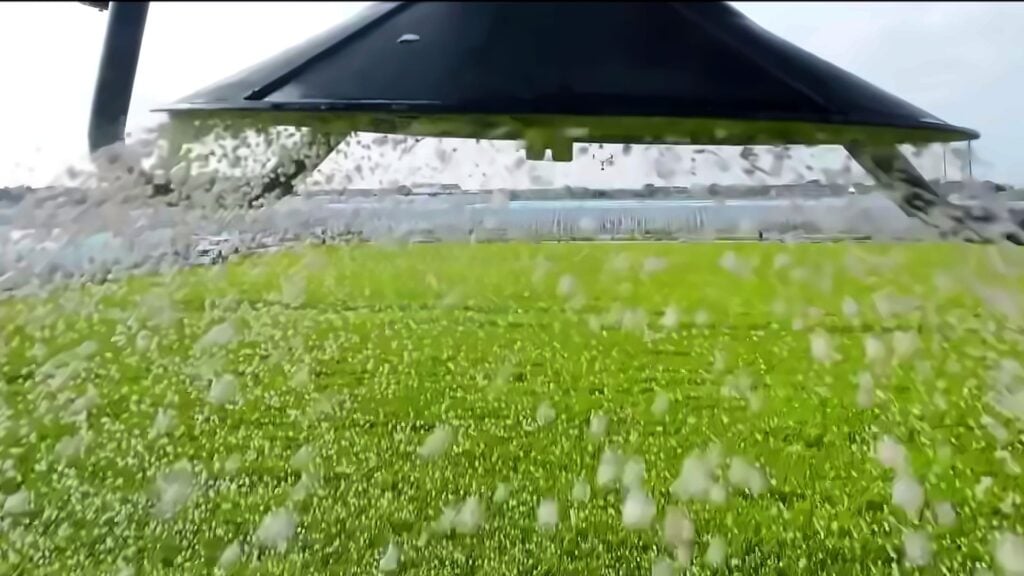 Aerial view of a drone spraying a green agricultural field.